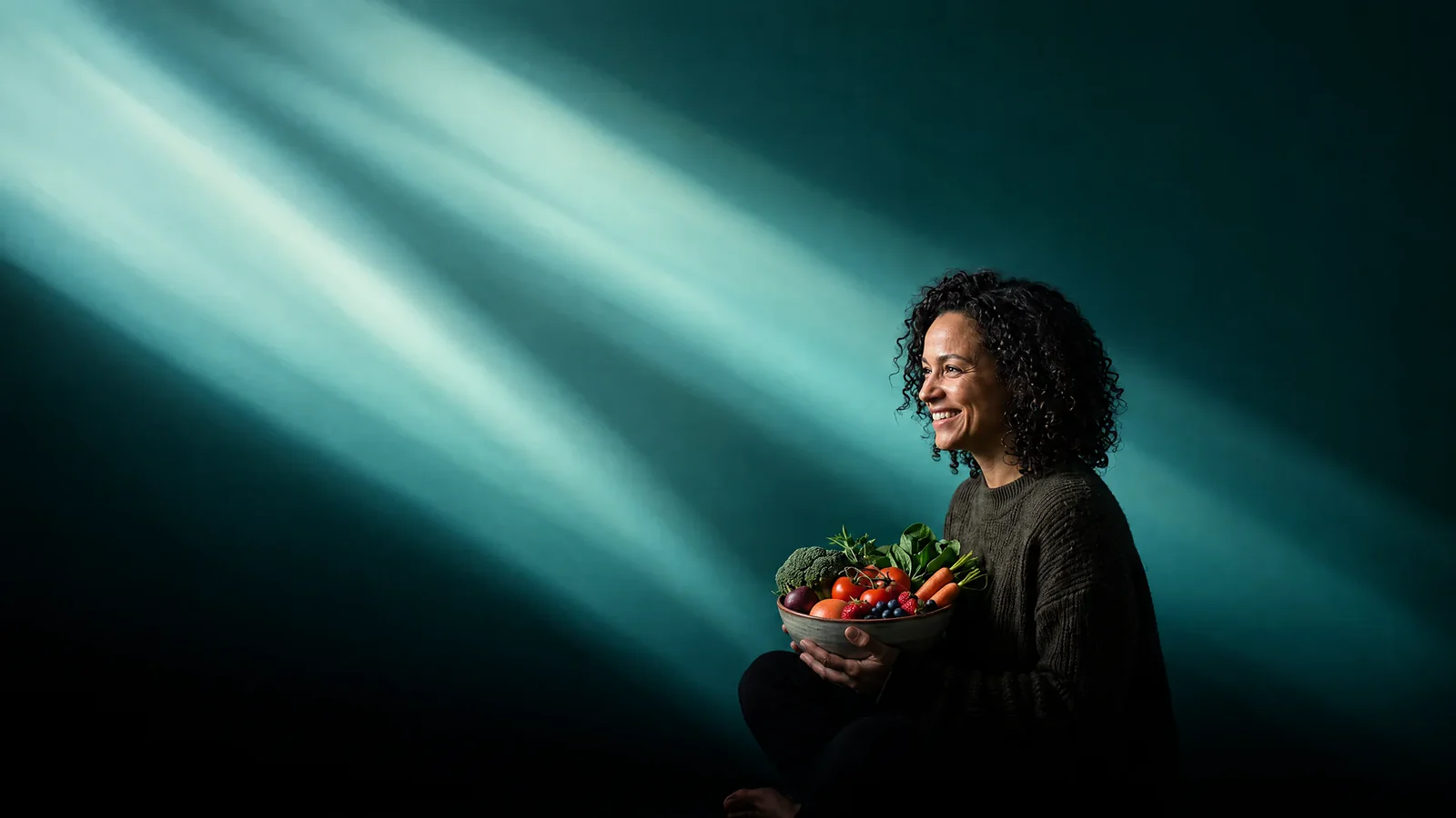 A woman holding a bowl of greens in teal light