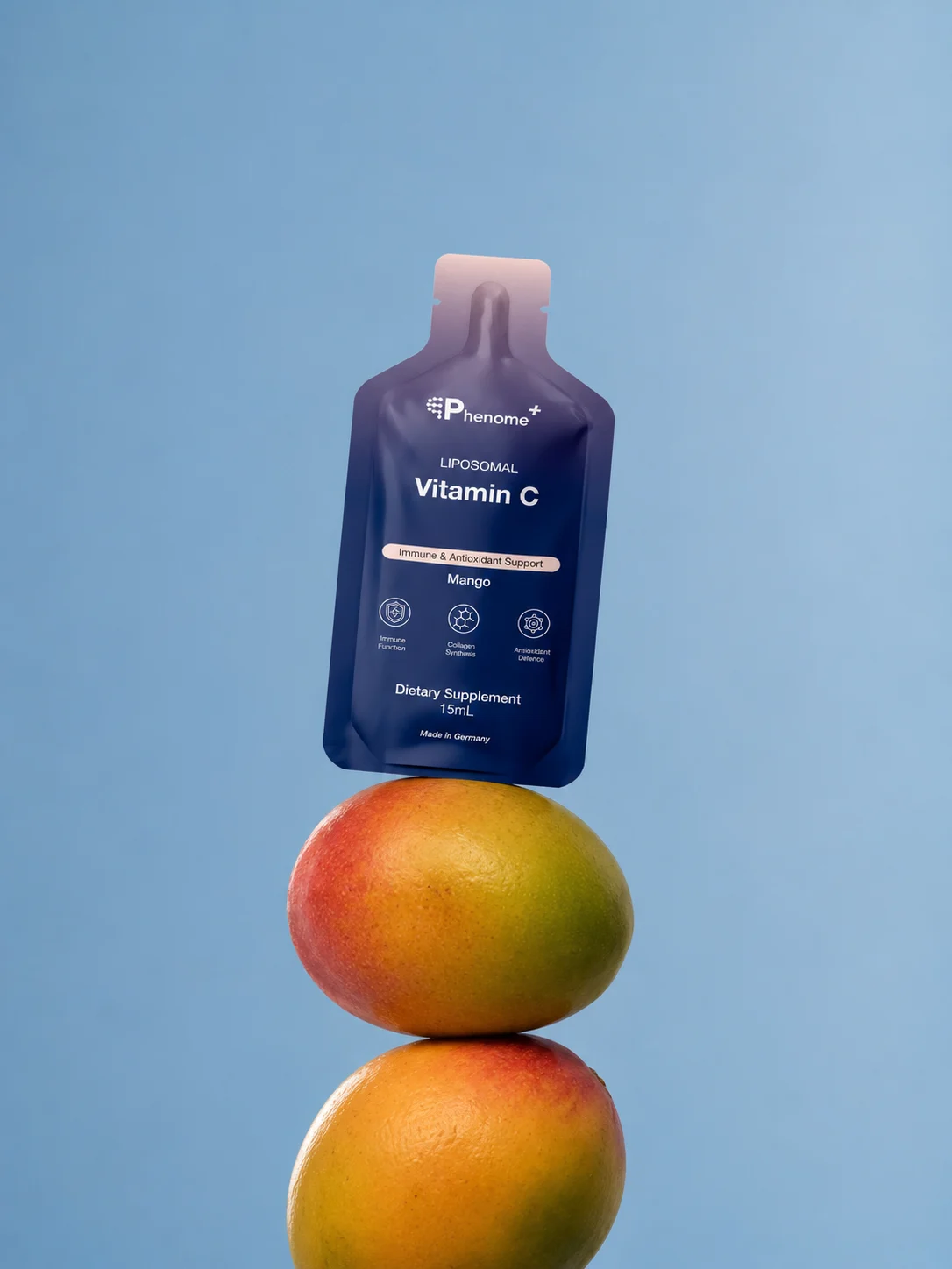 A sachet of Phenome+ Liposomal Vitamin C balanced on two mangoes