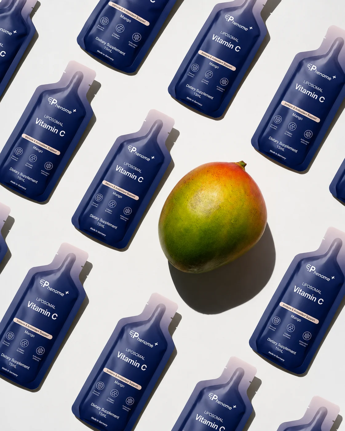 Sachets of Phenome+ Liposomal Vitamin C laid out in rows around a mango