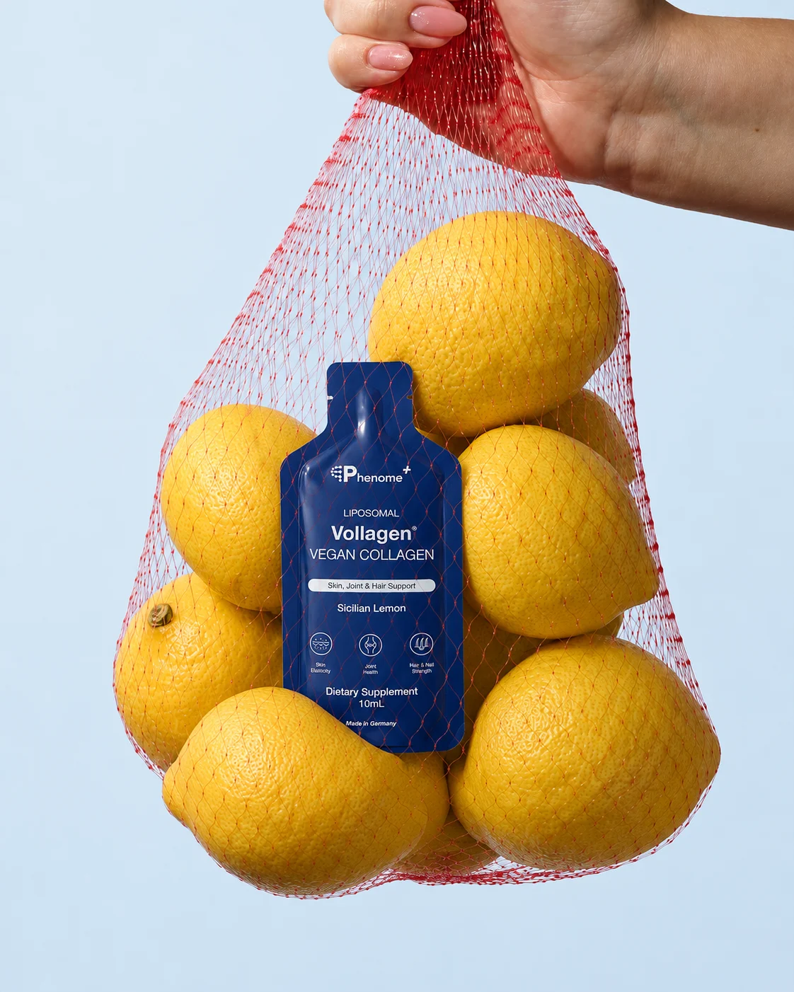 A sachet of Phenome+ Liposomal Vollagen in a net of lemons held in a hand